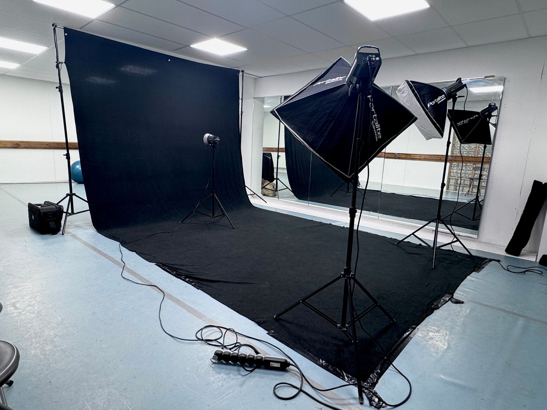Installation d'un studio photo avec fond noir, matériel d'éclairage et câbles