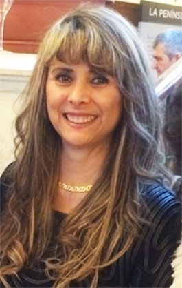 Una mujer con cabello largo y un collar sonríe para la cámara.