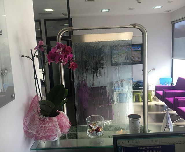 Una silla morada está sentada en una sala de espera al lado de una pared de vidrio.