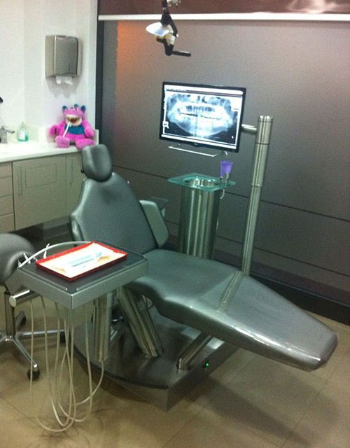 Un consultorio dental con una silla y un monitor