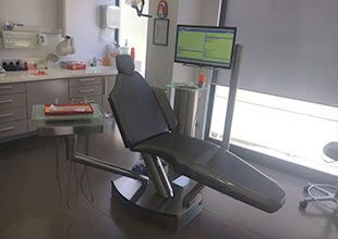 Un consultorio dental con un sillón dental y un monitor de computadora.