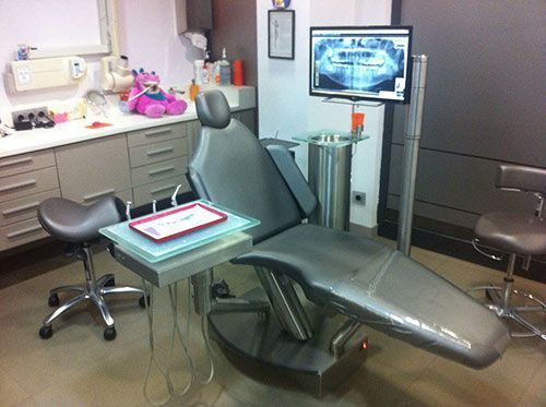 Un consultorio dental con un sillón dental y un monitor