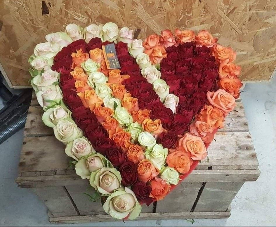 Coeur pour enterrement en roses rouges, oranges et blanches