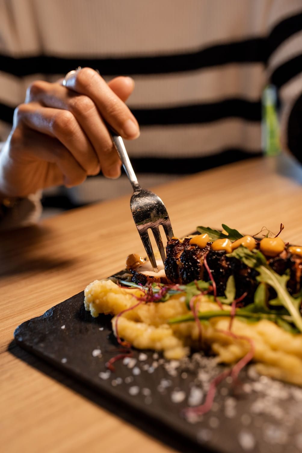 Persona comiendo un plato de puré de patatas y carne con un tenedor.