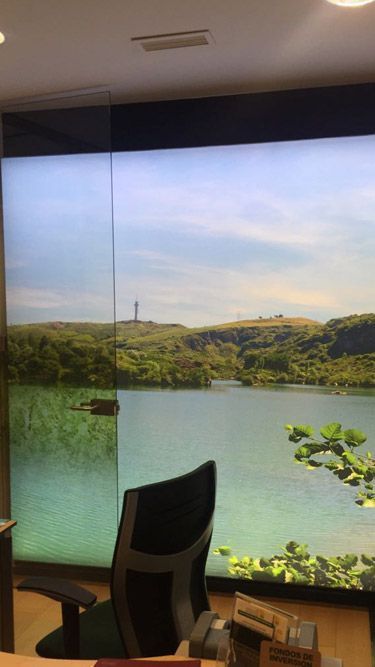 Una silla está colocada delante de una ventana grande con una imagen de un lago en ella.