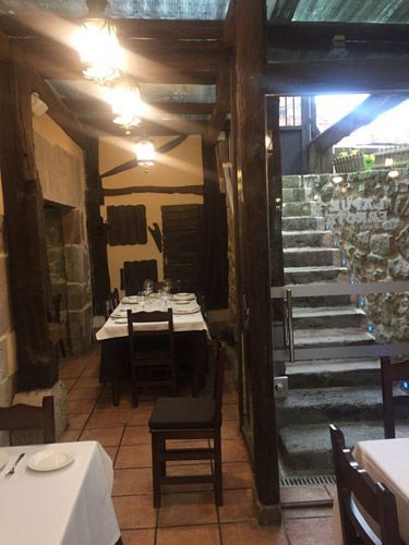 Un restaurante con mesas y sillas y escaleras al fondo.