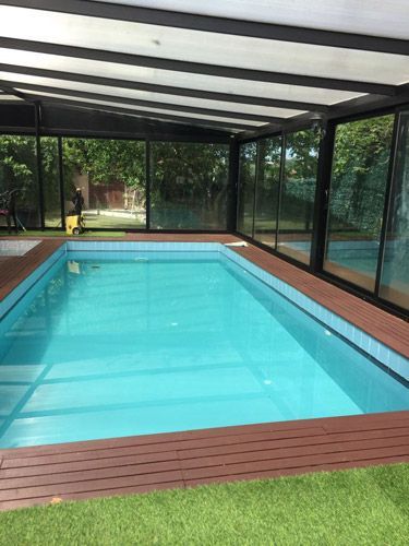 Una gran piscina cubierta con toldo y muchas ventanas.