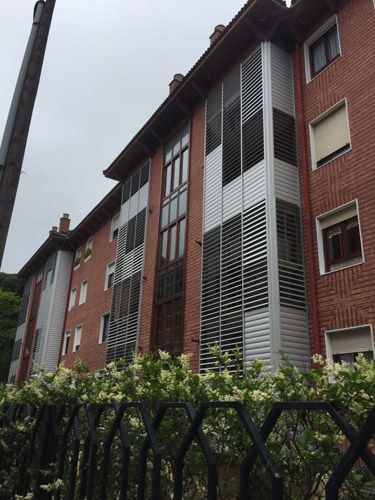 Un gran edificio de ladrillo con una valla delante.
