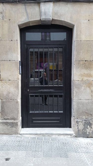 Una puerta negra con rejas está en una pared de piedra.