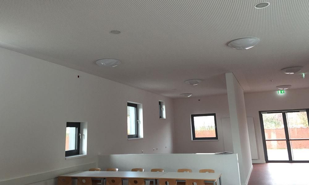 Ein großer Raum mit Tischen und Stühlen und einer weißen Decke