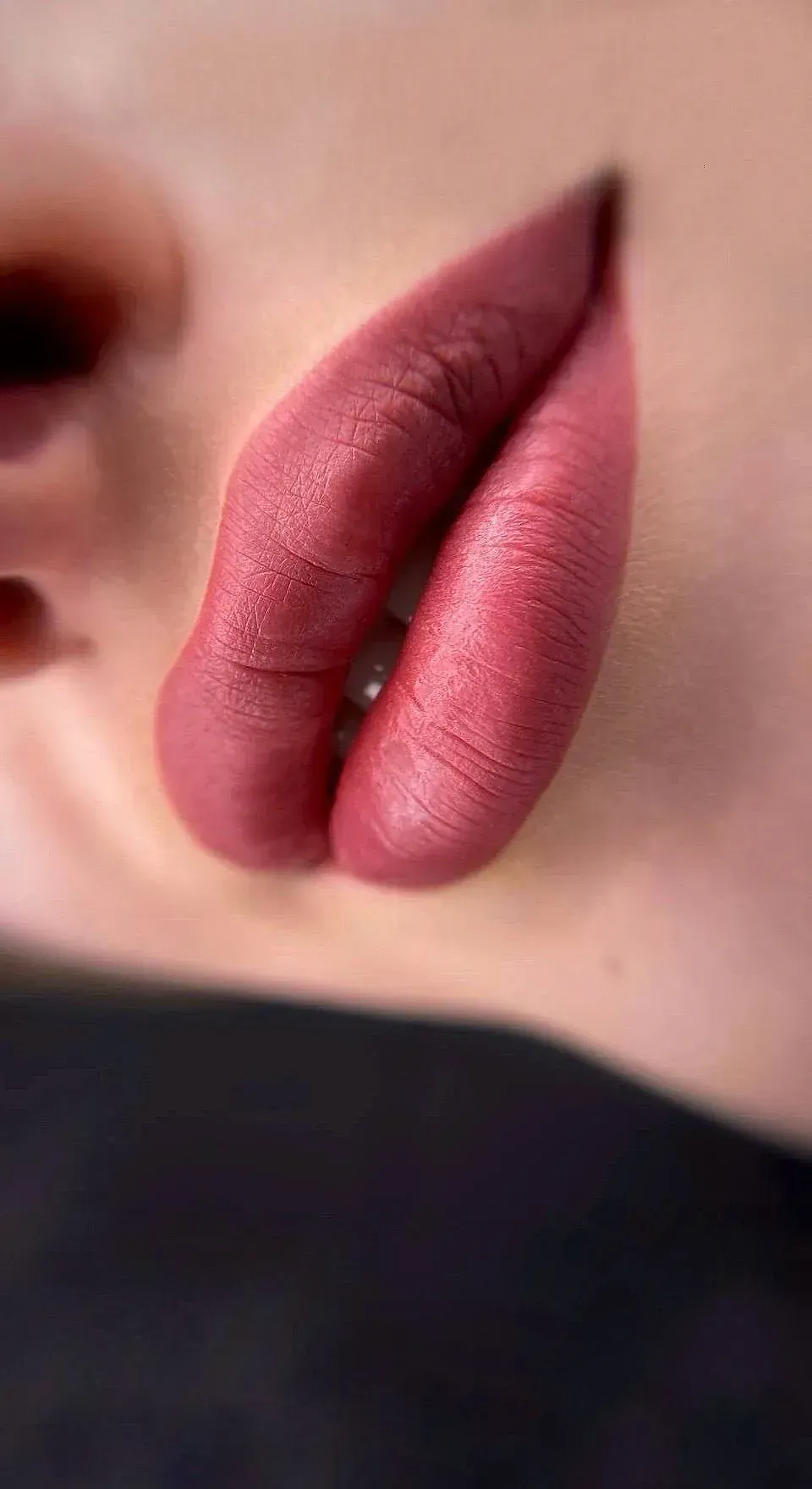 Un primer plano de los labios de una mujer con lápiz labial rosa.