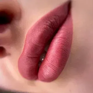 Un primer plano de los labios de una mujer con lápiz labial rosa.