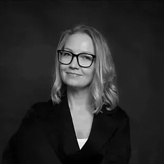 Una fotografía en blanco y negro de una mujer que lleva gafas y traje.