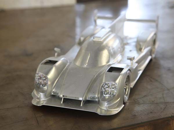 Auf einem Holztisch steht ein silbernes Rennauto.