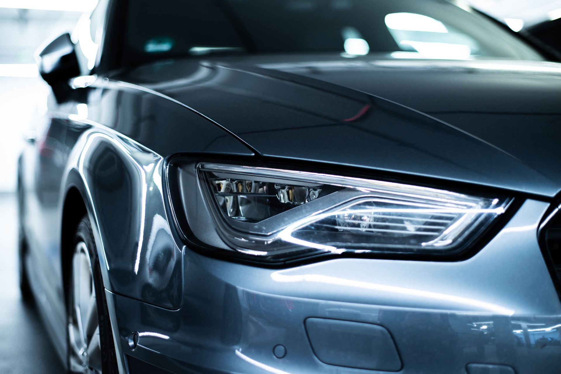 Gros plan sur le phare avant d'une voiture grise.