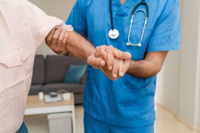 un homme avec une blouse et un stéthoscope soutenant le bras d'un home plus agé
