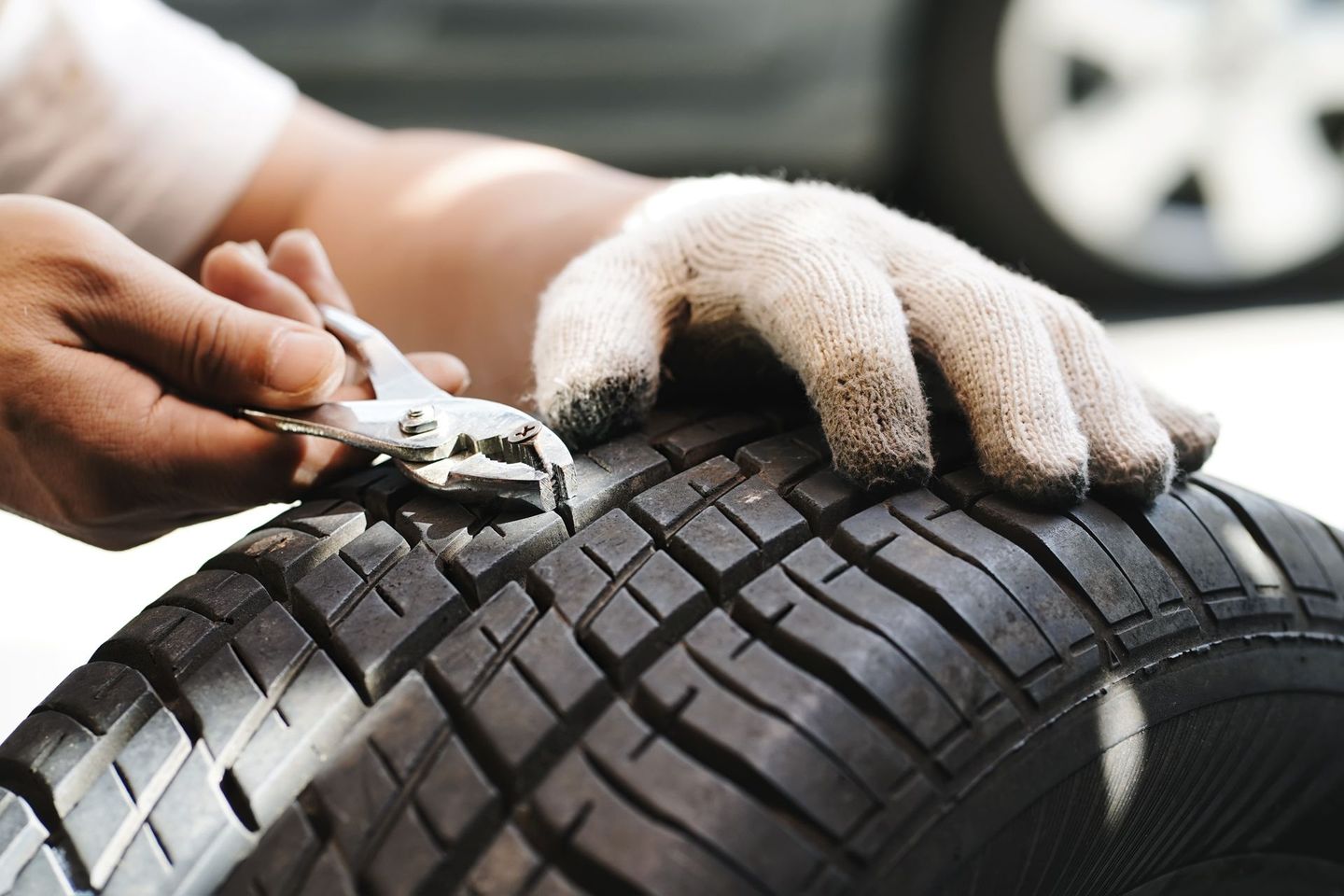 Main gantée tenant une clé réparant un pneu de voiture ; gros plan.