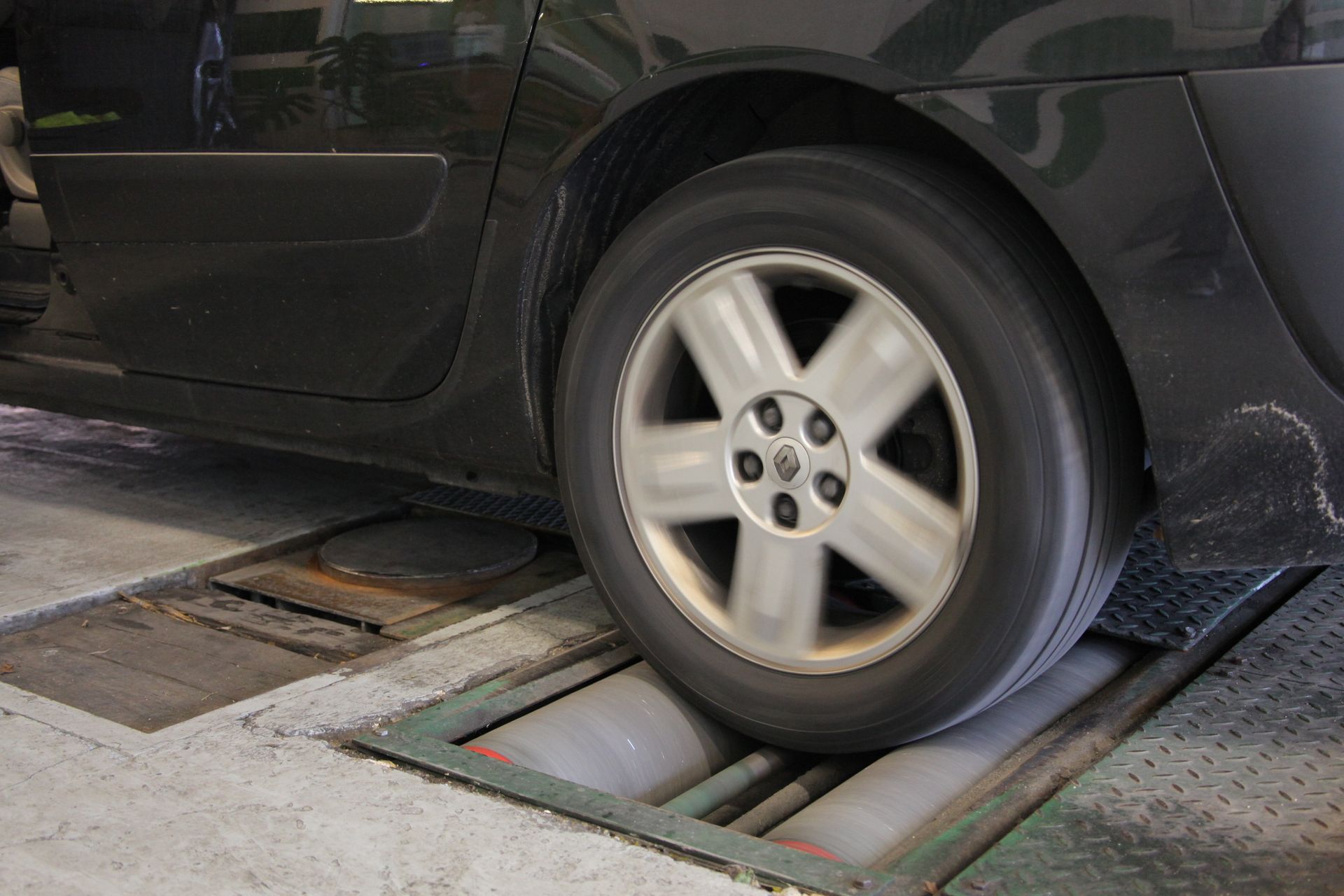 Pneu de voiture sur un rouleau compresseur, apparaissant flou en raison du mouvement, à l'intérieur d'un garage.