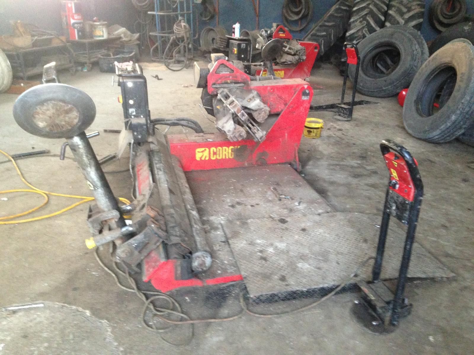 Machine à changer les pneus dans un garage, entourée de pneus et d'outils.