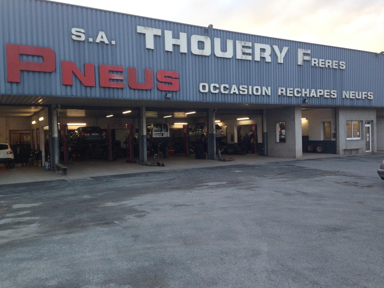 Enseigne SA Thouéry Frères Pneus, un atelier de pneumatiques. Bâtiment avec lettres, ateliers de travail visibles.