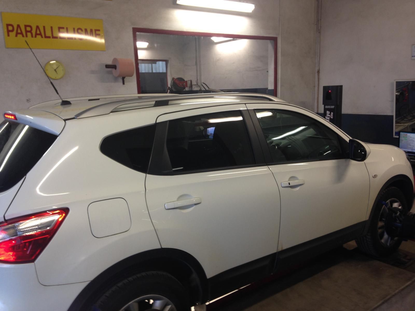 SUV dans un garage, en cours de réglage de la géométrie. Le panneau au-dessus indique Parallélisme.