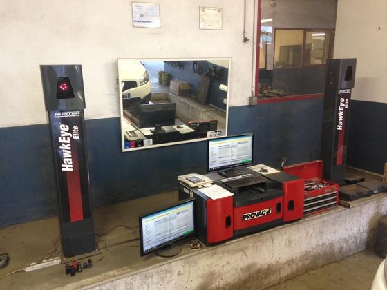 Machine d'alignement dans un garage avec écrans d'ordinateur, miroirs et équipement.