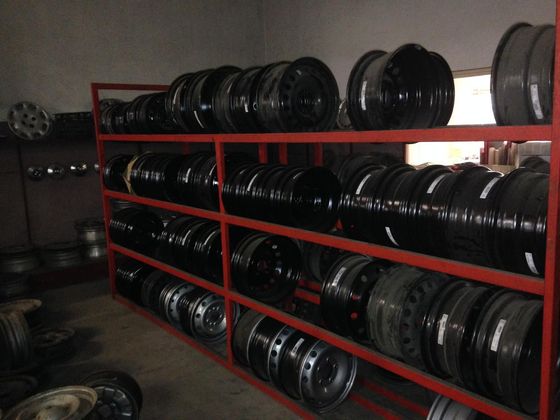 Des jantes en acier empilées sur des étagères dans un garage.