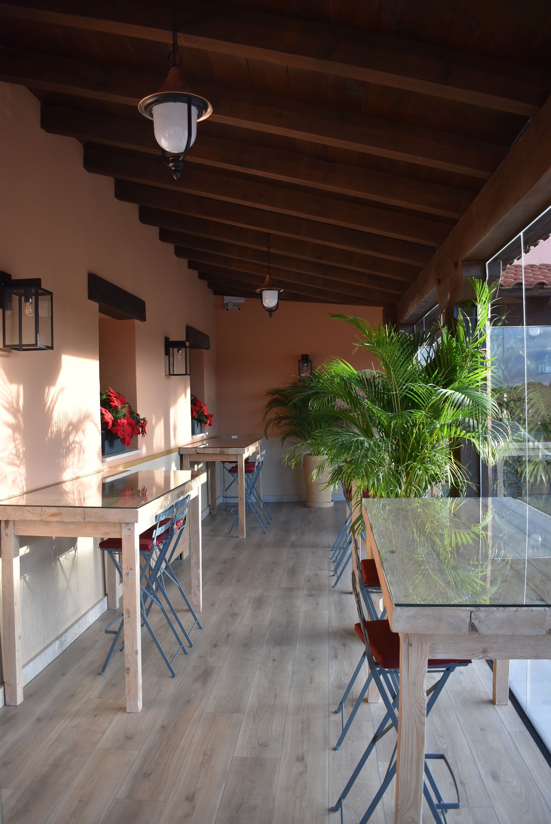 Una habitación larga con mesas y sillas bajo un techo de madera.