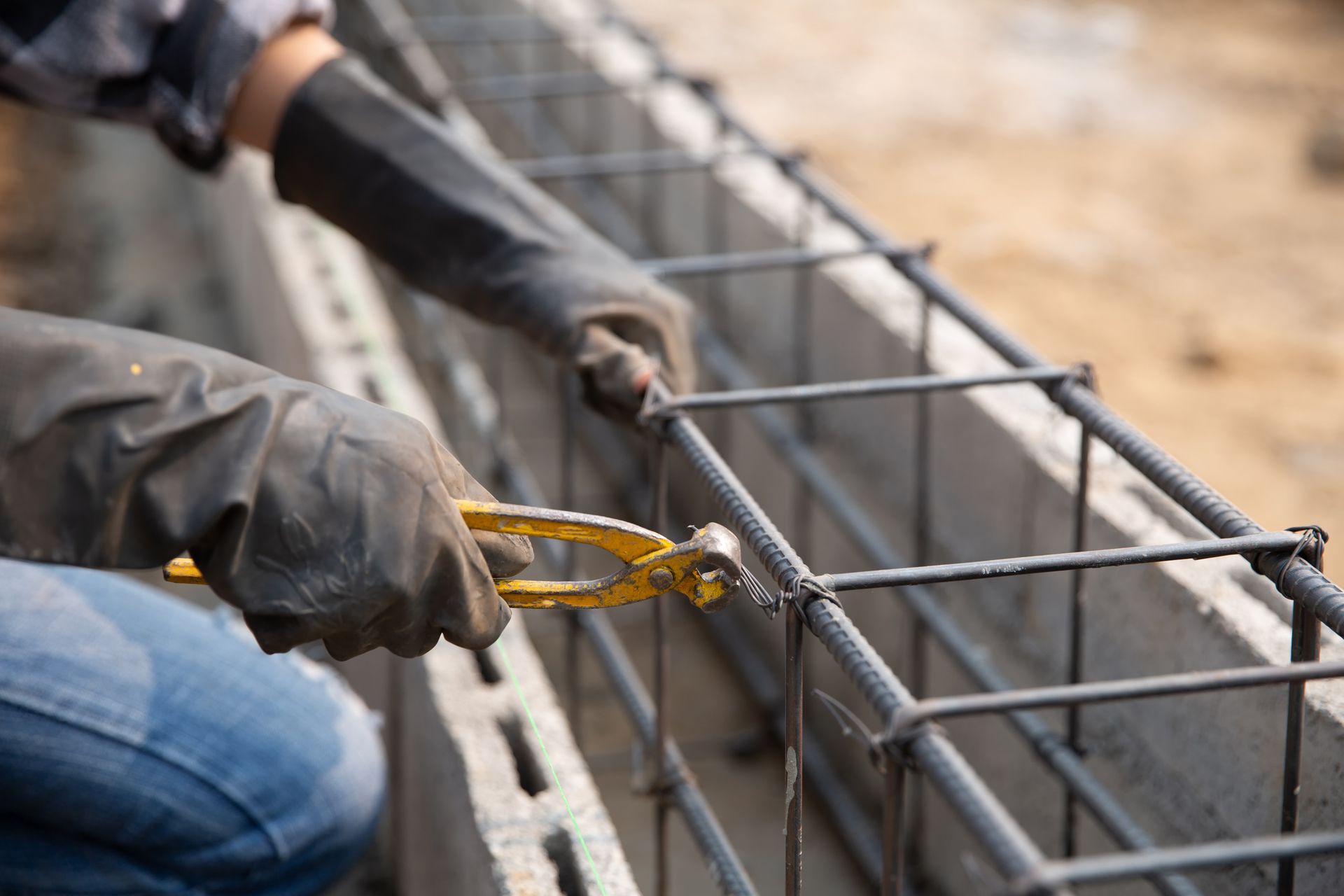 Un trabajador de la construcción está trabajando en un muro de hormigón con un par de alicates.