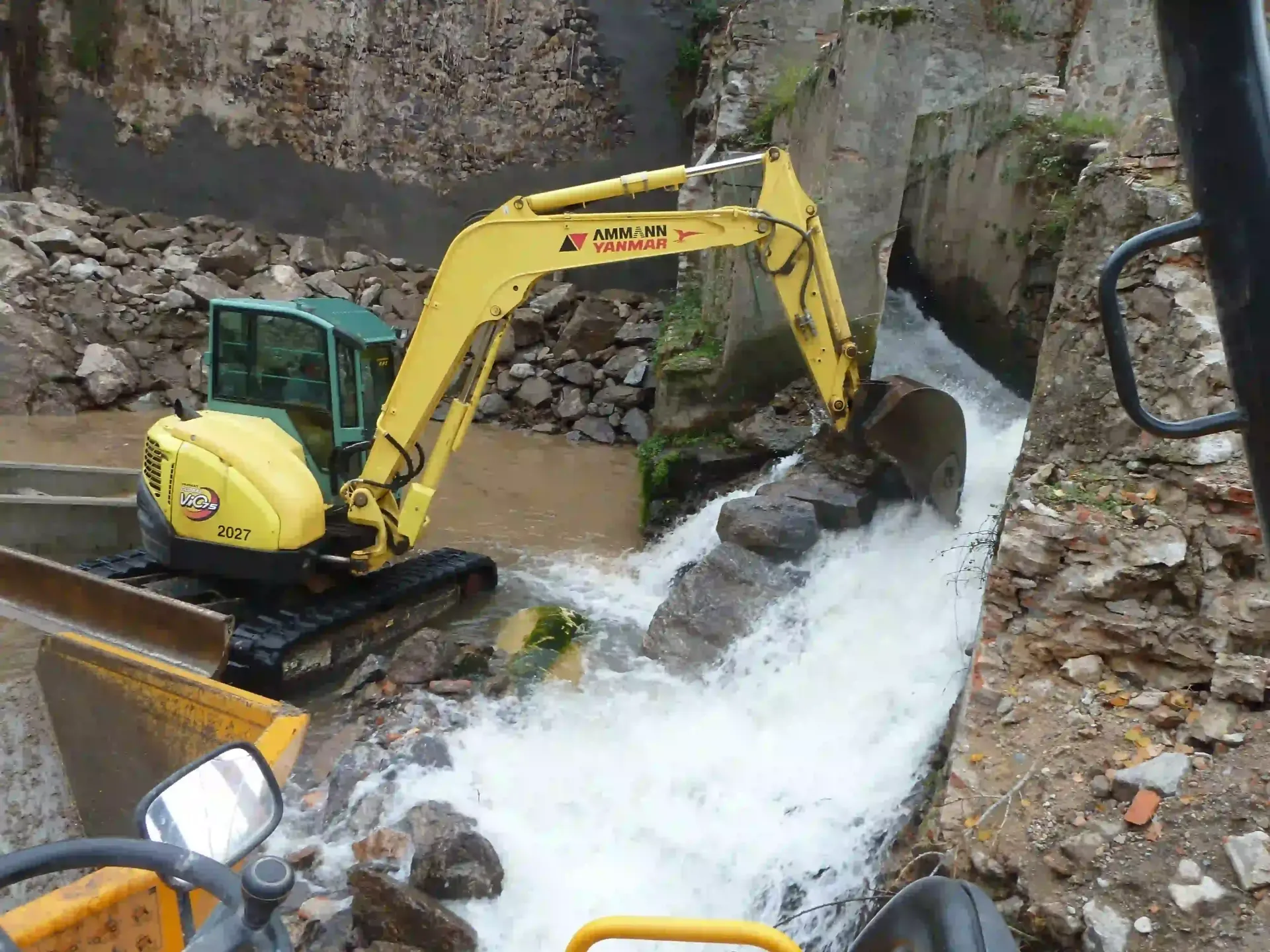 Una excavadora amarilla está trabajando en una cascada.