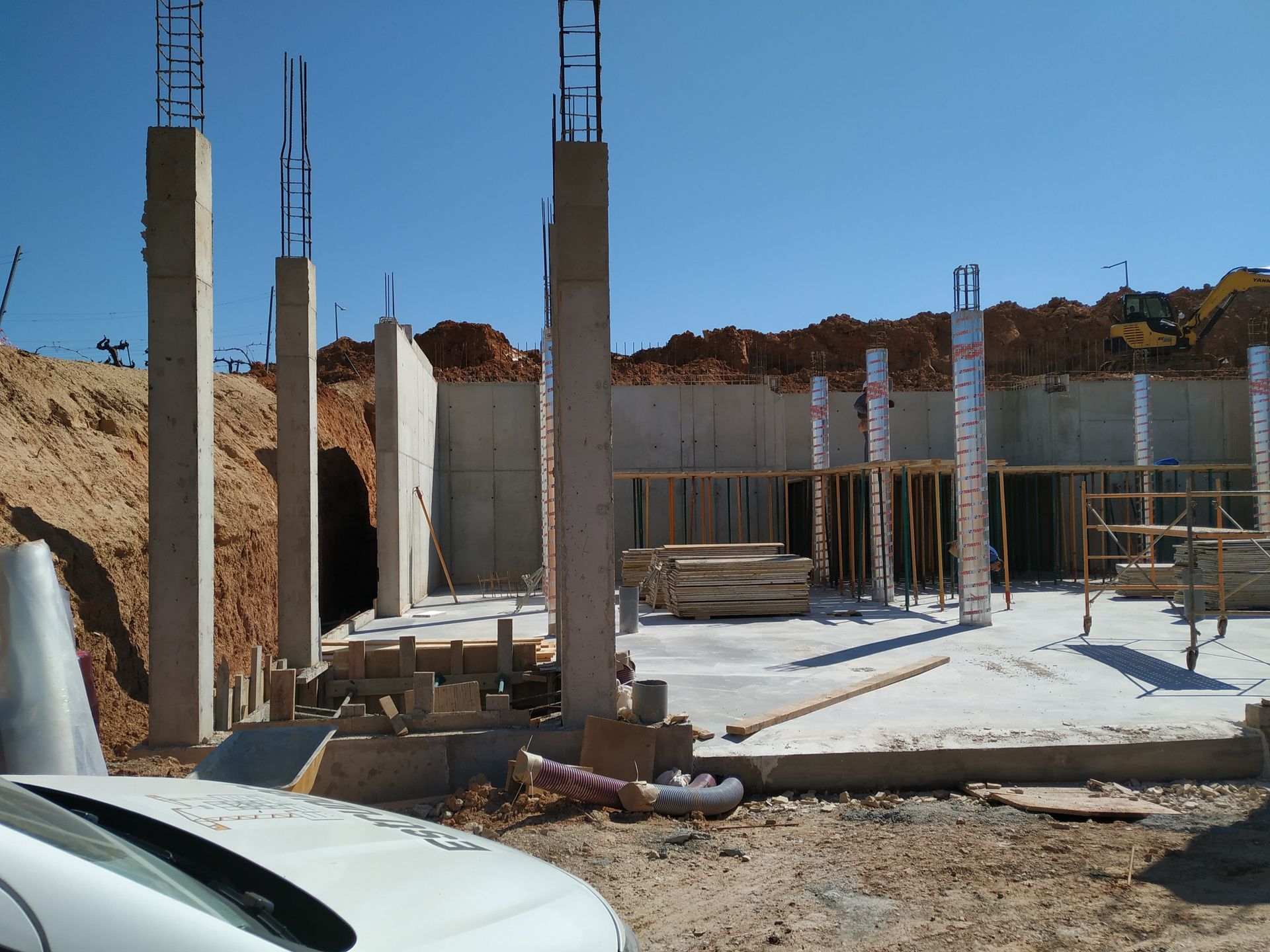 Un coche blanco está aparcado delante de una obra en construcción.