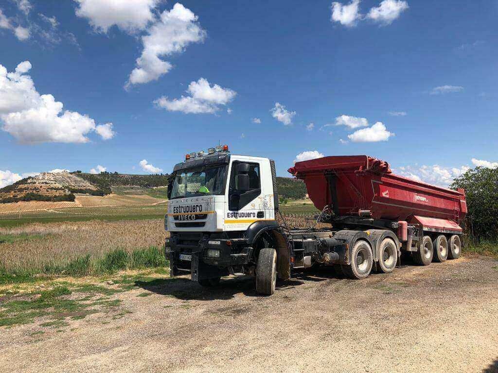 Un camión de volteo está estacionado al costado de un camino de tierra.