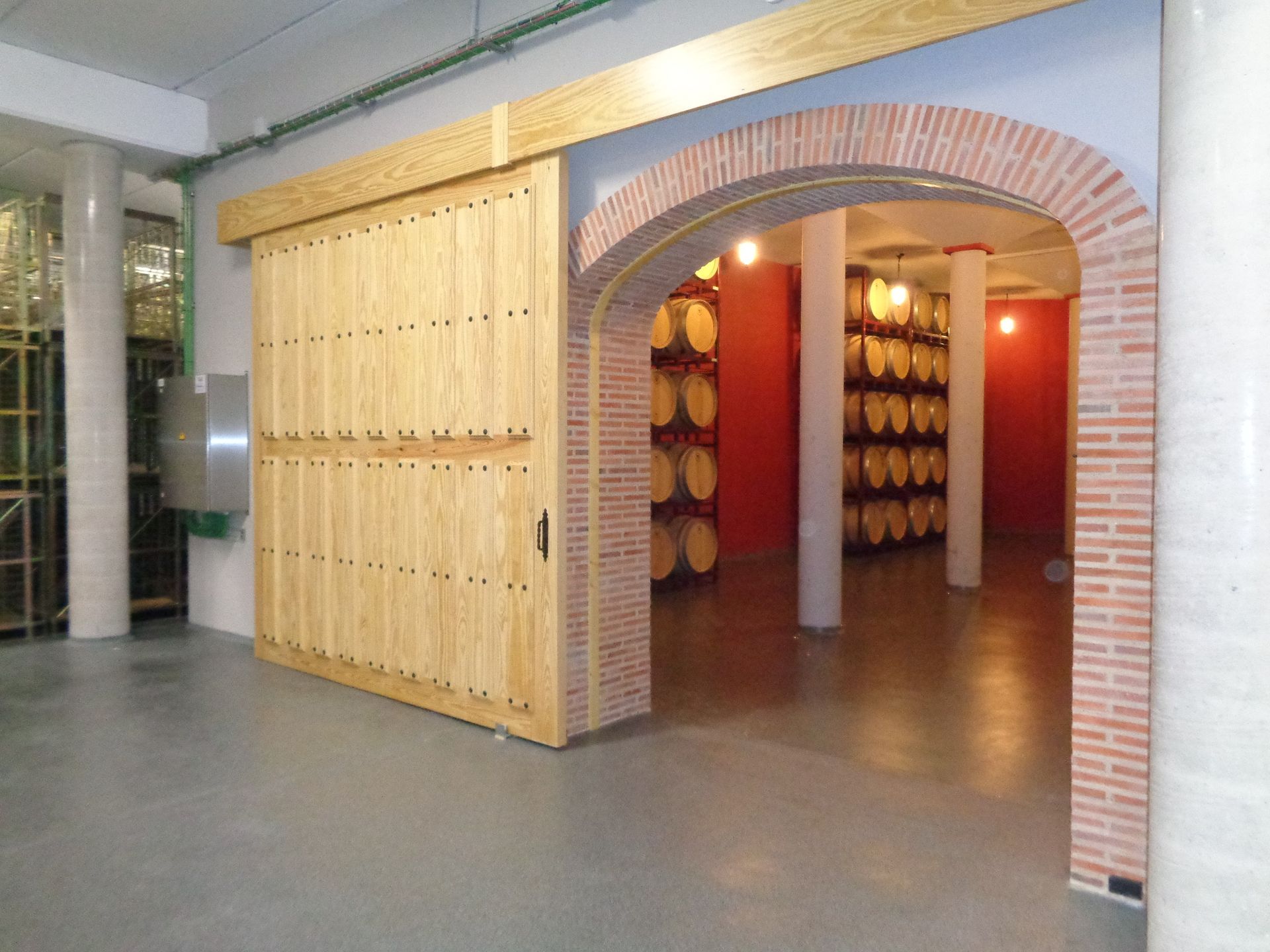 Una habitación con barriles y una puerta de madera.
