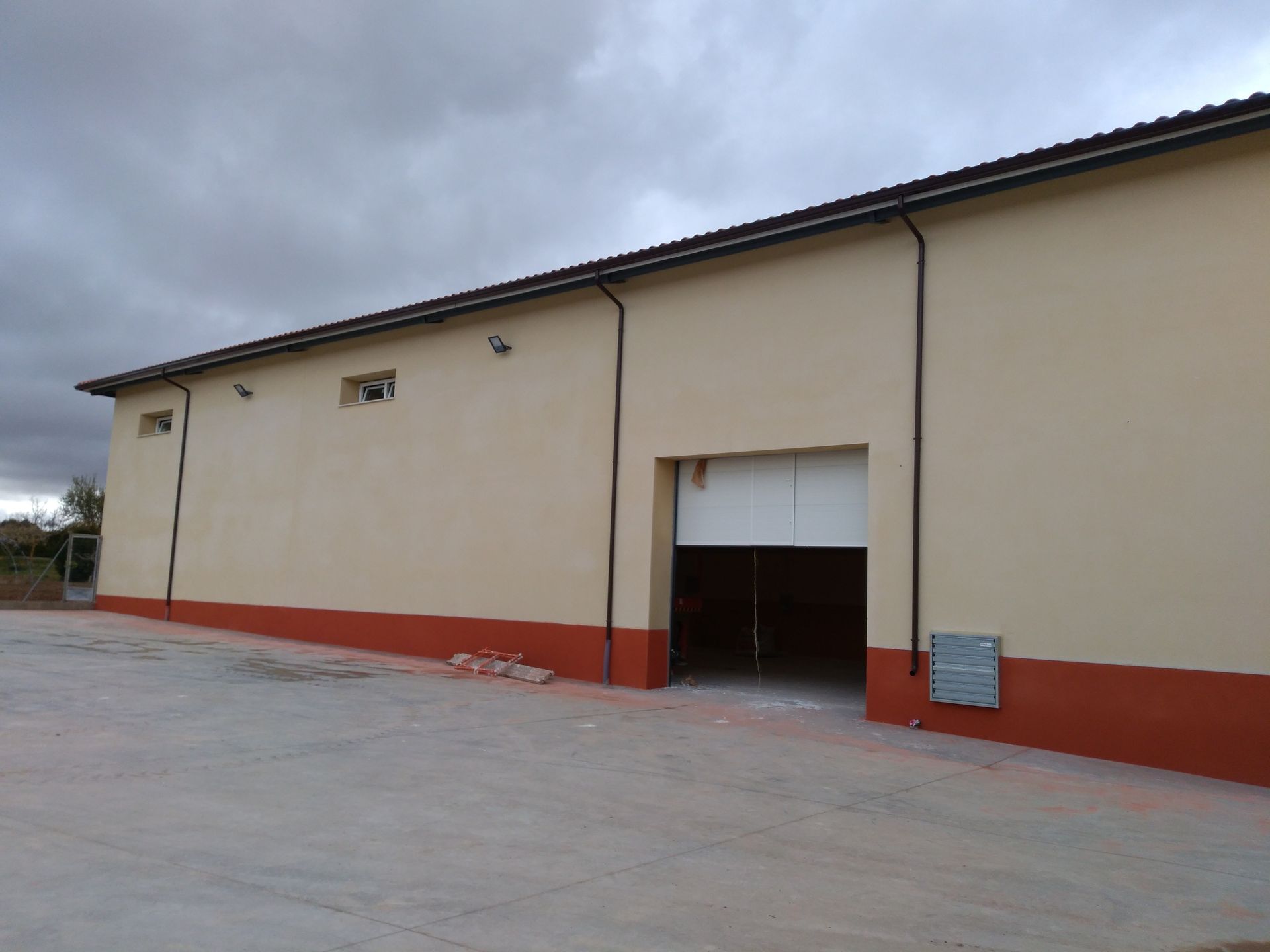 Un gran edificio con una puerta de garaje y un cielo nublado al fondo.