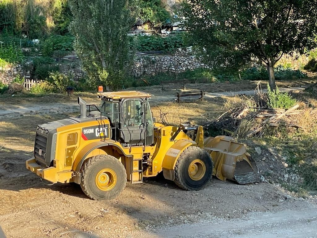 Una excavadora amarilla está estacionada al costado de un camino de tierra.