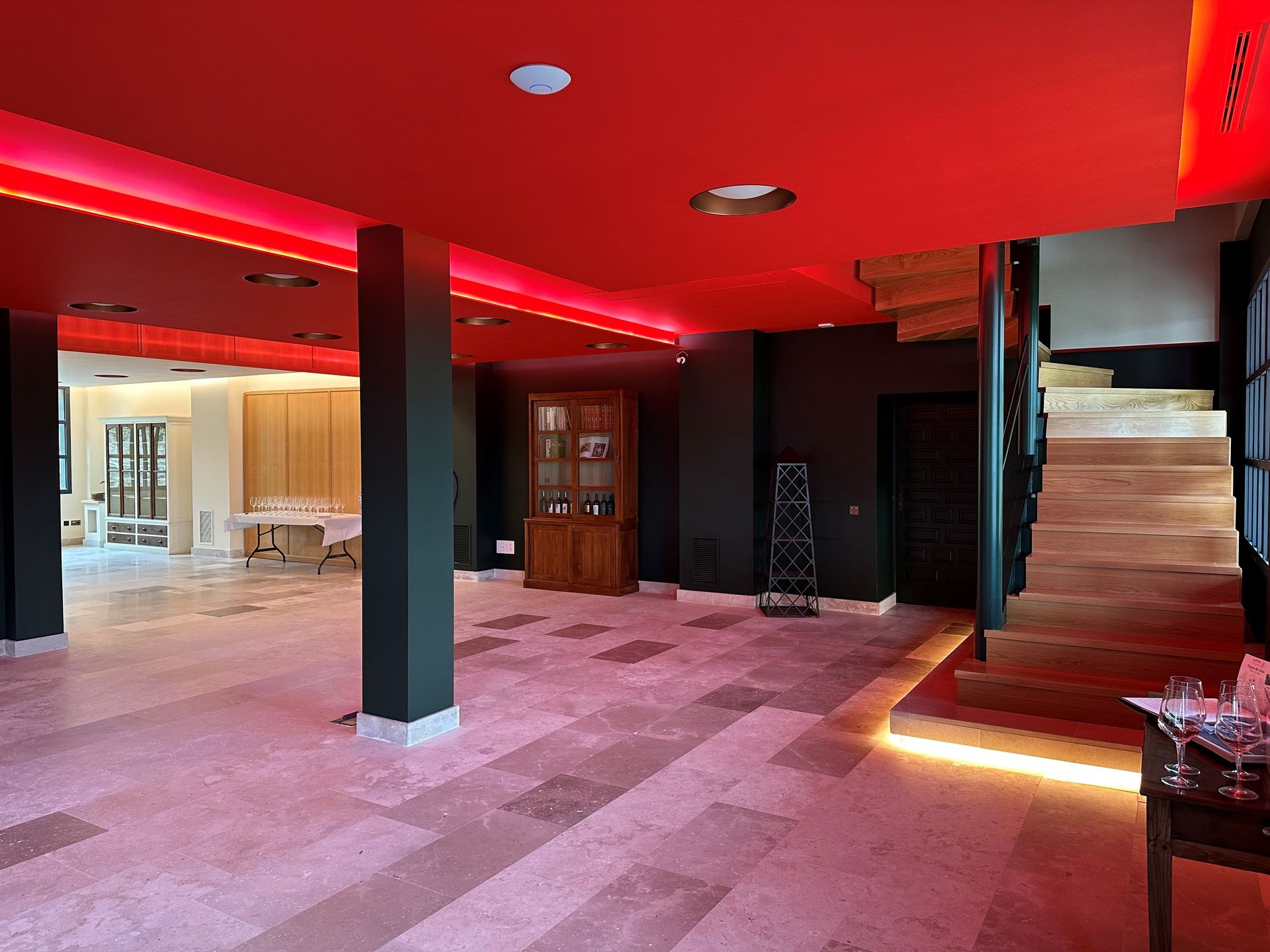 Una habitación grande con techo rojo y una escalera de madera.