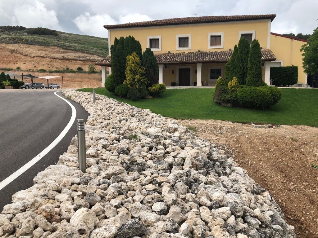 Una gran casa amarilla está rodeada de rocas y césped.