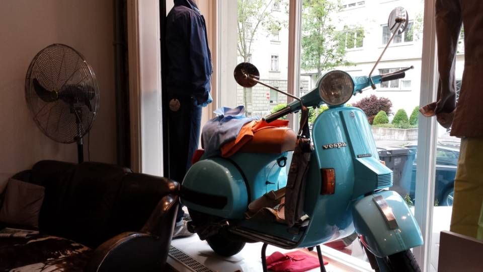 Hellblauer Vespa-Roller in einem Schaufenster.