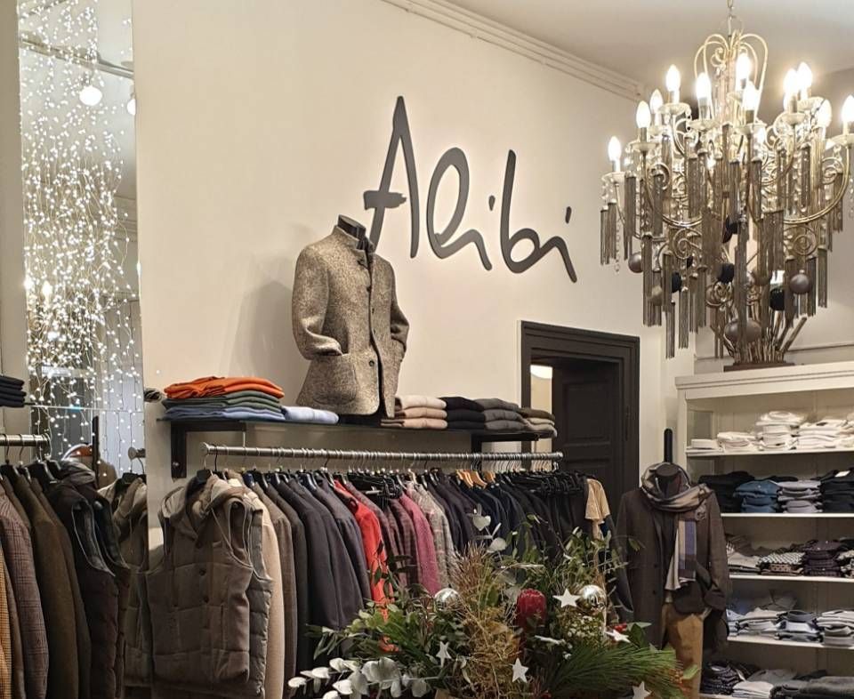 Innenansicht eines Bekleidungsgeschäfts mit einem „Alibi“-Schild über einer Schaufensterpuppe in Jacke. 