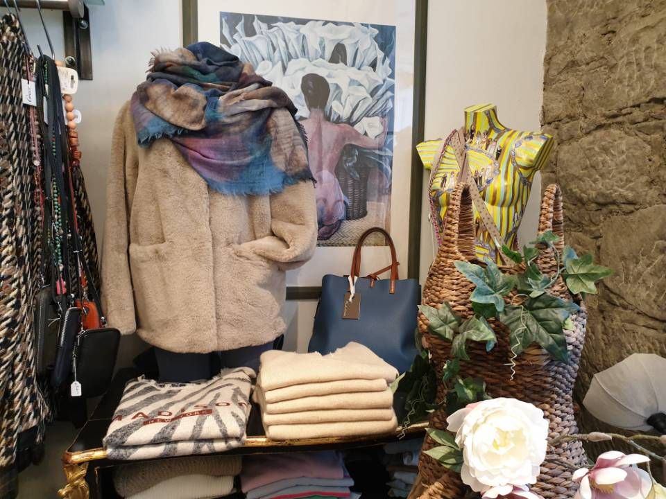 Kleiderauslage in einem Geschäft, zu sehen sind ein Mantel, ein Schal, Pullover und eine Handtasche.