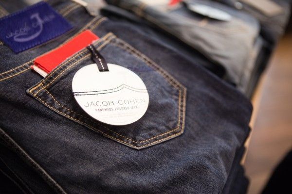 Nahaufnahme einer dunkelblauen Jeans mit einem Jacob Cohen-Preisschild an der Gesässtasche.