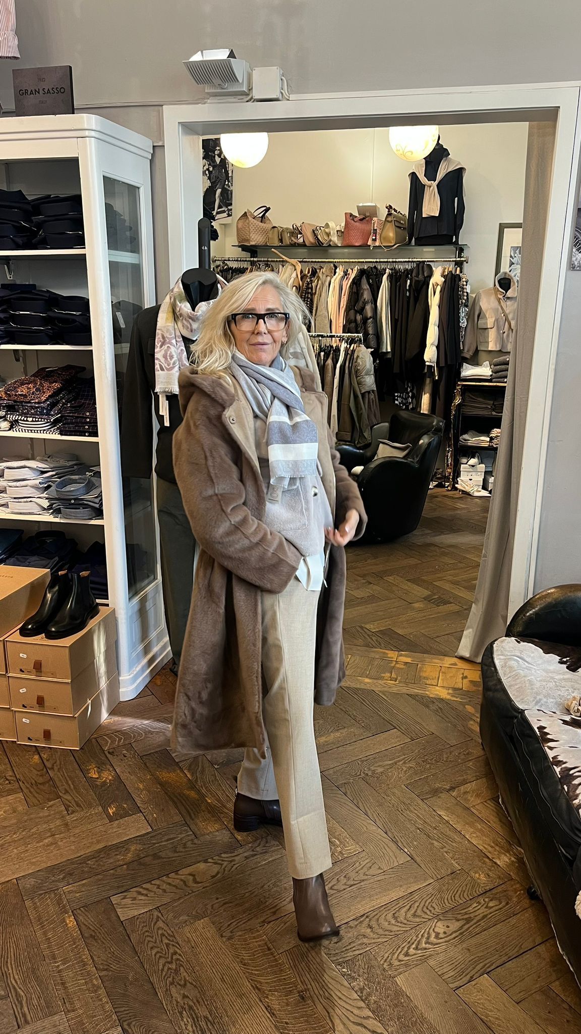 Frau mit Mantel und Schal in einem Bekleidungsgeschäft.