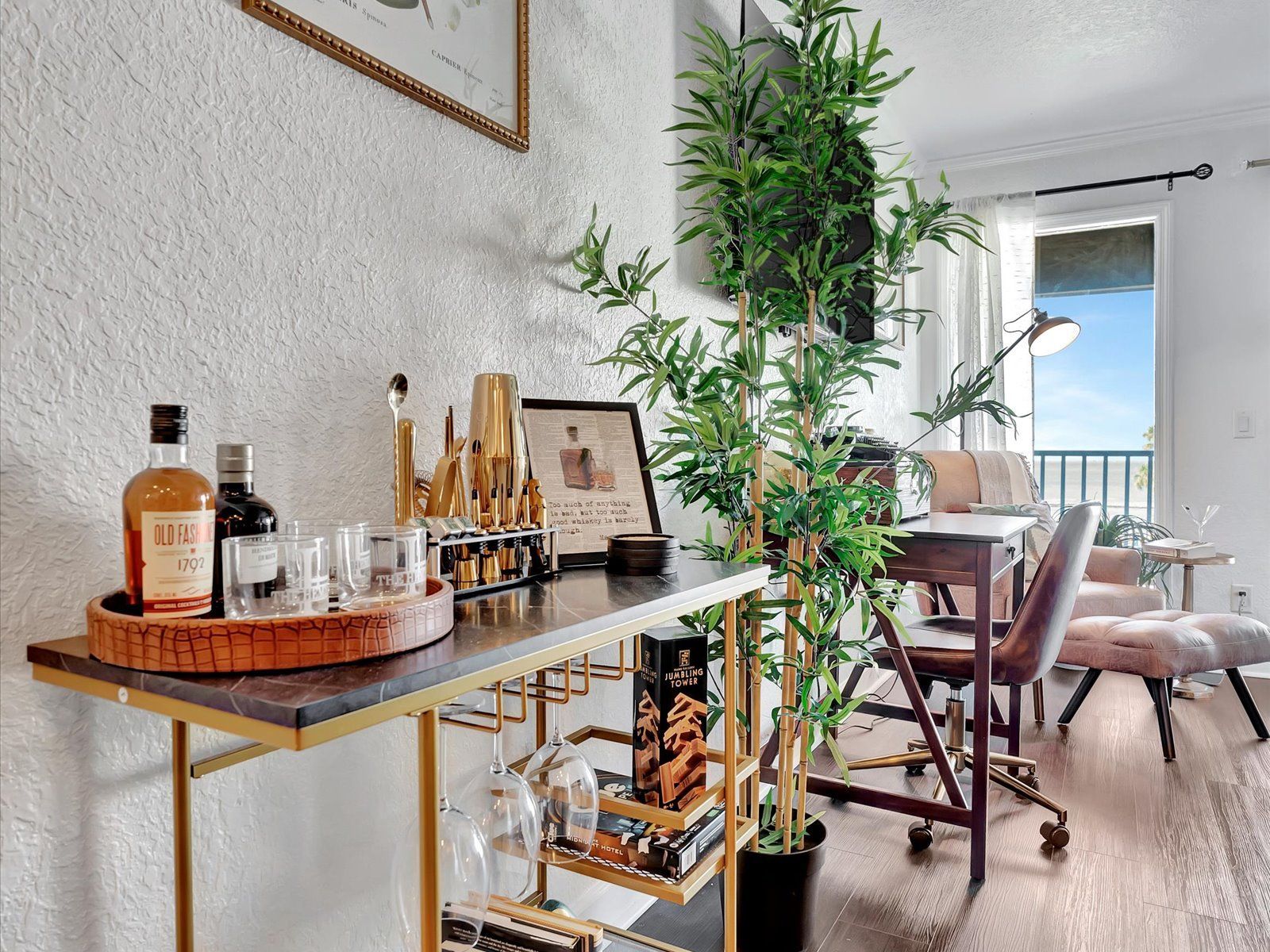 A bar cart with a bottle of whiskey and glasses on it in a living room.