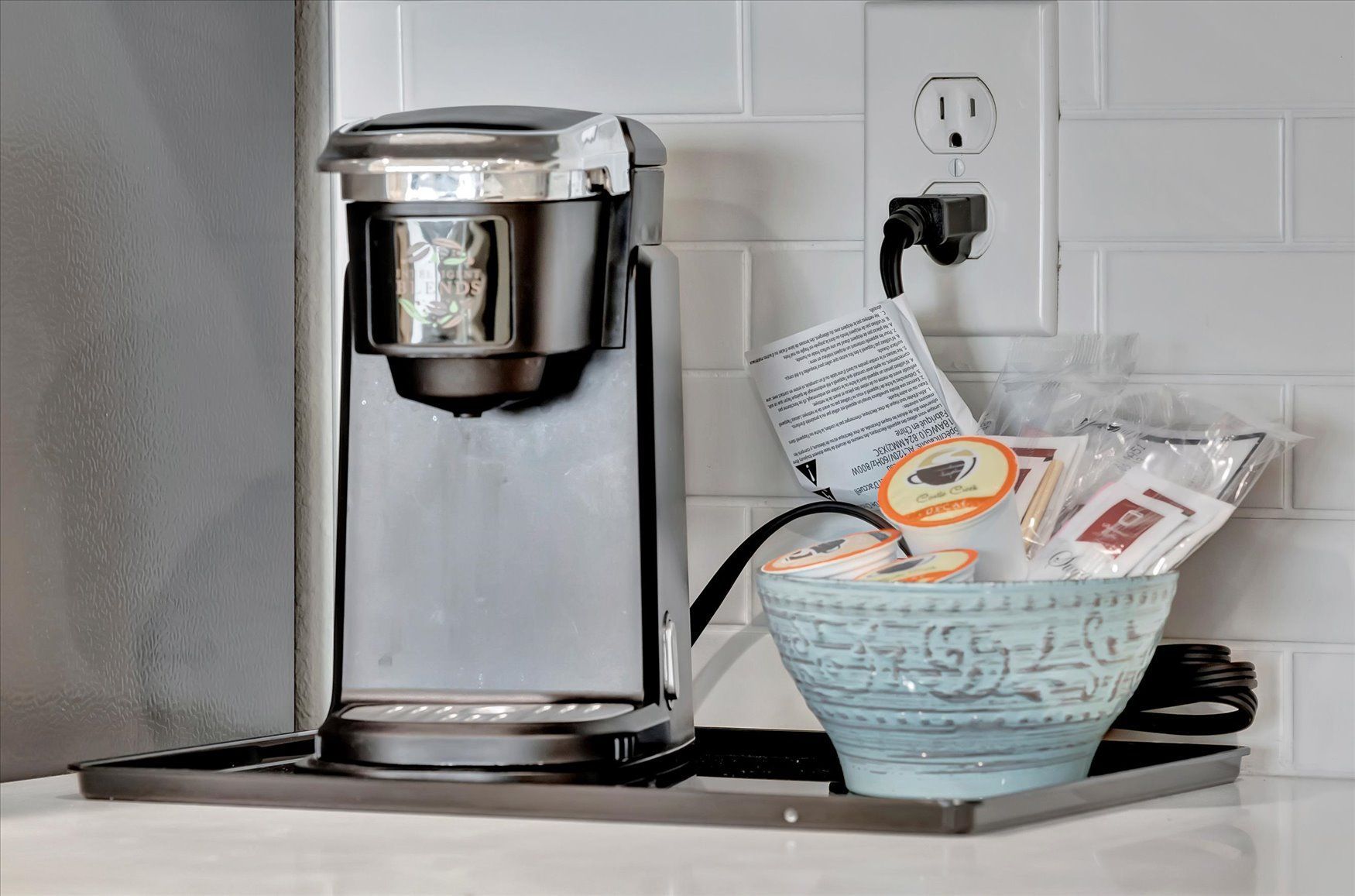 A coffee maker is sitting on a counter next to a bowl of coffee.