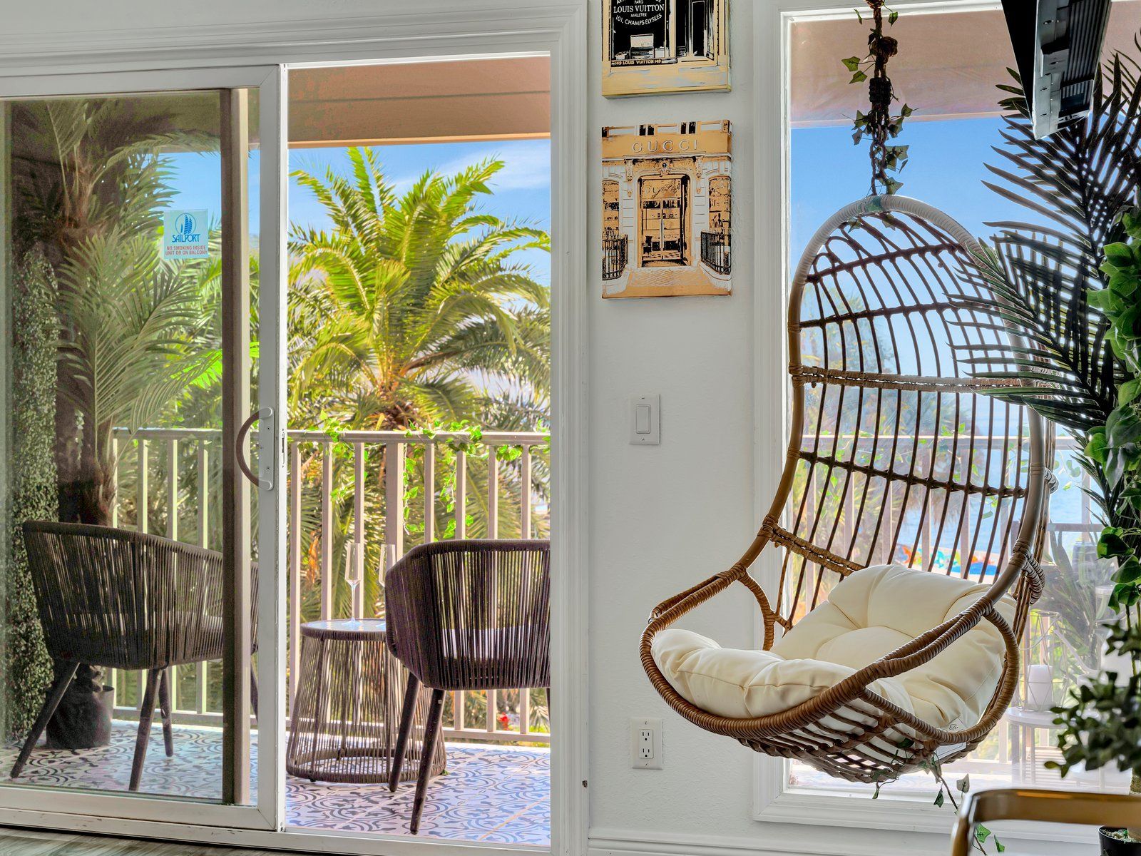 A living room with a hanging chair and a sliding glass door leading to a balcony.