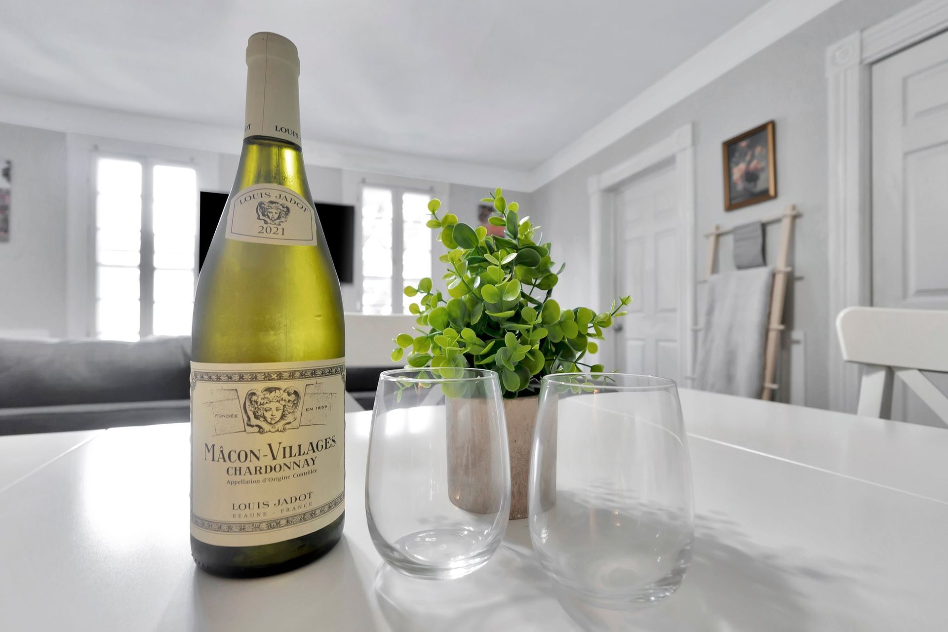 A bottle of wine is sitting on a table next to two glasses.