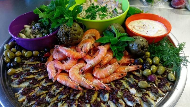 Ein Teller mit Garnelen, Oliven und anderem Gemüse auf einem Tisch.