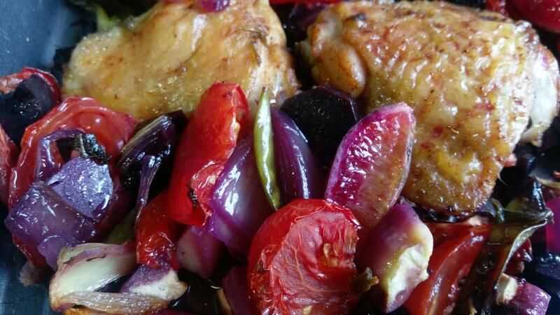 Eine Nahaufnahme eines Tellers mit Hühnchen, Tomaten, Zwiebeln und Paprika.