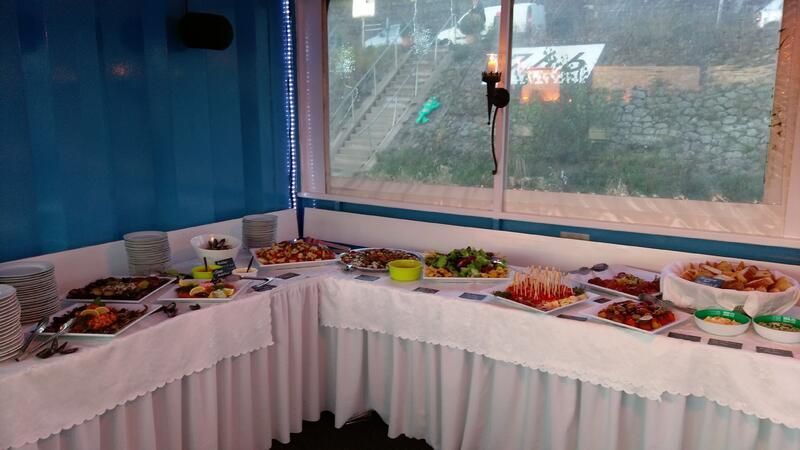 Ein Buffet-Tisch mit viel Essen vor einem Fenster.