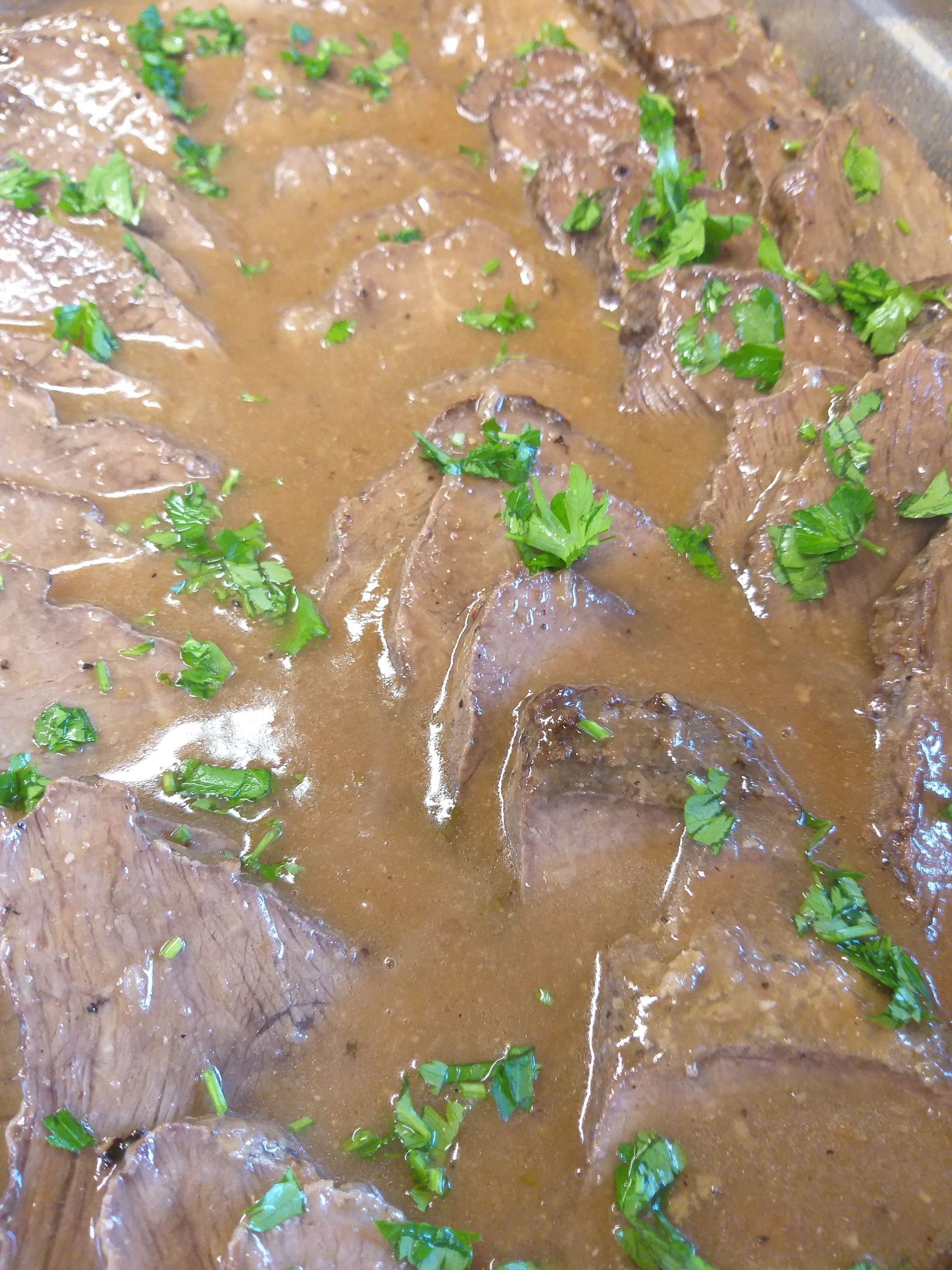 Eine Nahaufnahme eines Tellers mit Fleisch und Soße.